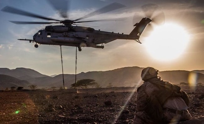Cpl. Christopher Russell, a landing support specialist with 11th Marine Expeditionary Unit, watches as a CH-53E Super Stallion lifts a concrete barrier during helicopter external load training at Arta Beach, Djibouti, Feb. 16, 2017. 