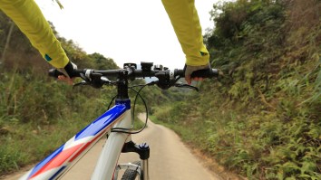 Mountain Biker Goes Full Send And Jumps A Ramp Over The Road And Above Tour De France Riders Mid-Race