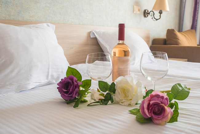 flowers and wine on hotel bed