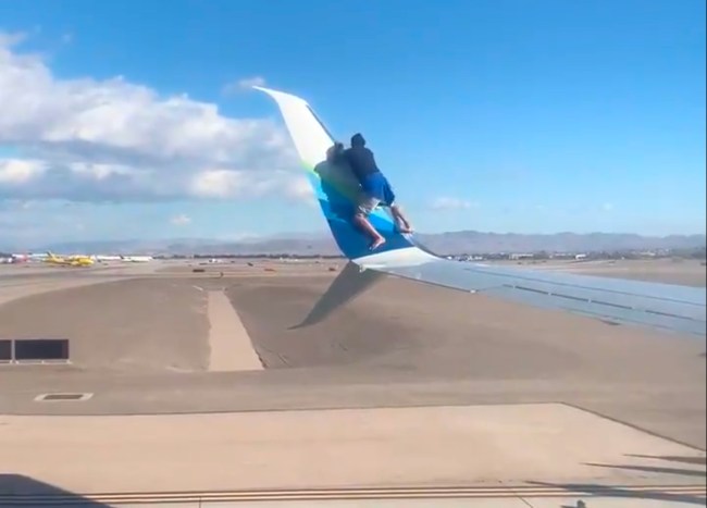 Guy Climbs On Wing Of Plane
