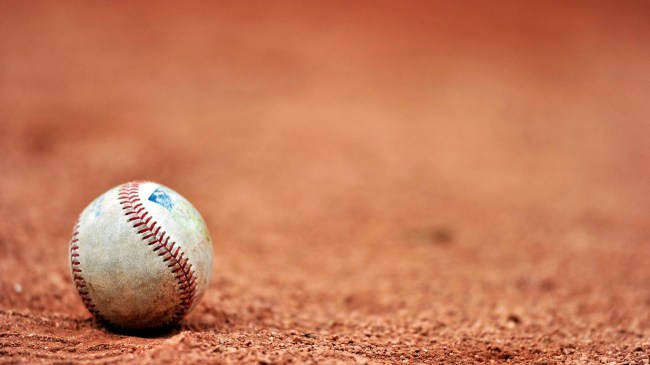 A baseball rests on the infield clay.