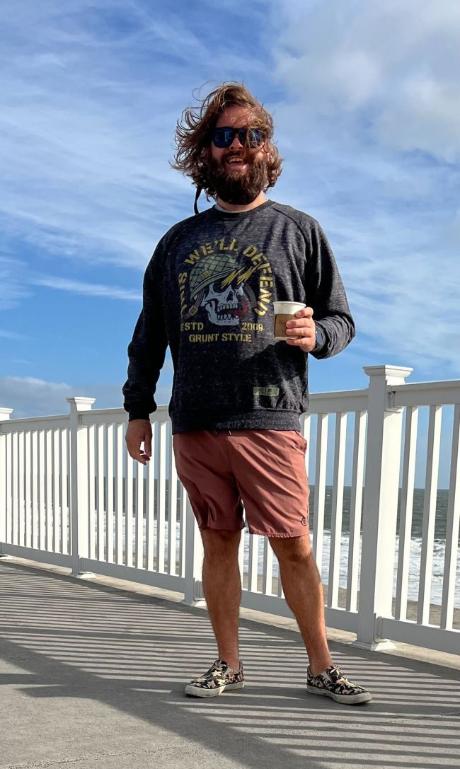 A bearded man standing outside at the beach