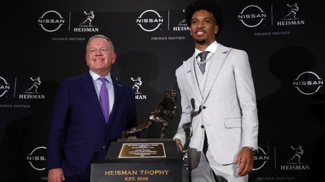Jayden Daniels accepts the Heisman trophy with LSU head coach Brian Kelly.