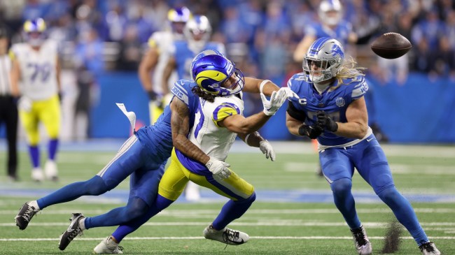 Rams WR Puka Nacua tries to haul in a pass between a pair of Lions defenders.
