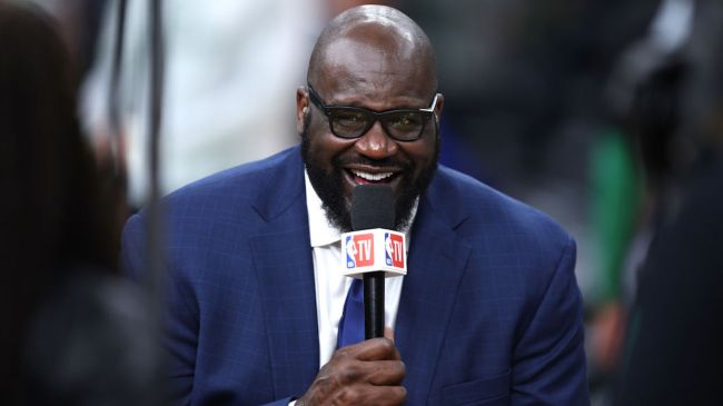 shaq laughing while holding a mic