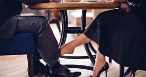 Girl flirts with a guy in a restaurant. She touches his leg with her bare foot under the table