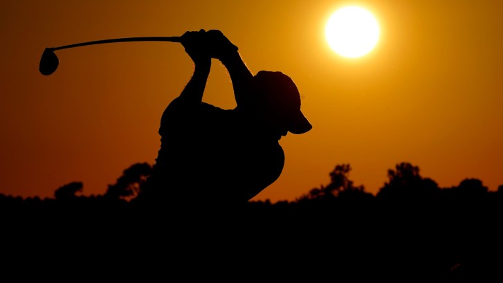 Tiger Woods swinging in front of a sunset